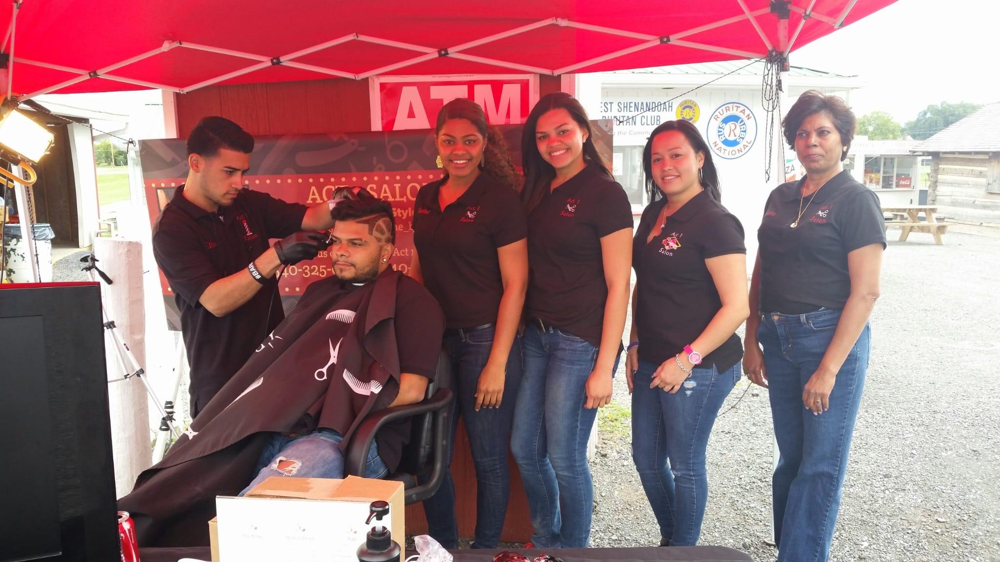 Act 1 group gathered beneath a red canopy at an outdoor community event